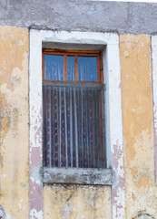 Fototapeta na wymiar Window with Sheer Curtains in a Building with Chipped Gold Paint over Stucco