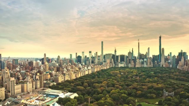 Aerial drone footage of New York midtown skyline at sunset viewed from above Central Park, with slow forward camera rotation