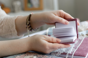 Women's hands are holding a small handmade notebook.