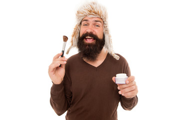 Freak visagiste. Applying makeup face tone. Powder cosmetics. Man bearded stylist wear hat hold...
