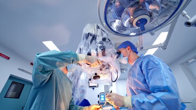 Operating Room With Surgery In Progress. Medical team performing surgical operation in bright modern operating room