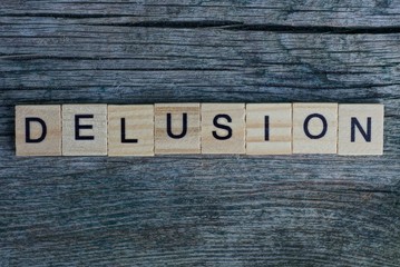 word delusion made from  wooden letters lies on a gray background
