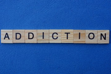 word addiction made from  wooden letters lies on a blue background