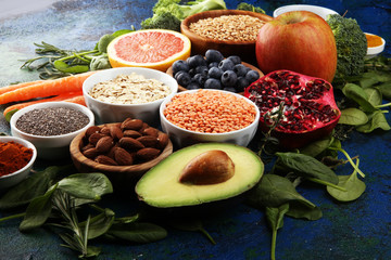 Healthy food clean eating selection: fruit, vegetable, seeds, superfood, cereals, leaf vegetable on rustic background
