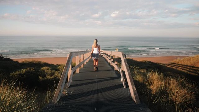Young Blonde Girl Walking Down Ocean Boardwalk in Beautiful Golden Morning Light in Phillip Island Australia, Smiths Beach 