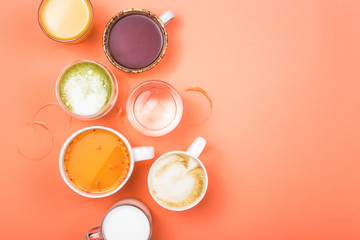 Fototapeta na wymiar Different drinks cappuccino, tea, sea buckthorn juice, milk, water, orange juice and matcha on a bright coral pink background. Top view, flat lay, copy space.
