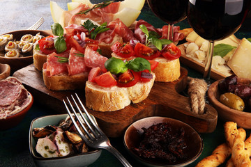 Italian antipasti wine snacks set. Cheese variety, Mediterranean olives, seafood salad, Prosciutto di Parma, tomatoes, anchovy and wine in glasses