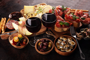 Italian antipasti wine snacks set. Cheese variety, Mediterranean olives, seafood salad, Prosciutto di Parma, tomatoes, anchovy and wine in glasses