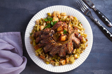 Crown roast of pork stuffed with apples and bread crumbs and celery sticks on white plate