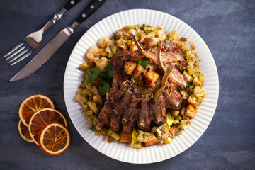 Crown roast of pork stuffed with apples and bread crumbs and celery sticks on white plate