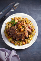 Crown roast of pork stuffed with apples and bread crumbs and celery sticks on white plate