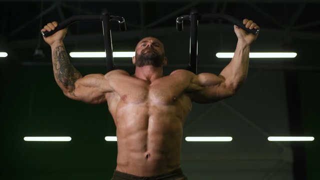 Muscular bodybuilder fitness men doing pull-ups exercises in gym naked torso. Handsome strong athletic men pumping up back muscles workout fitness and bodybuilding concept background.