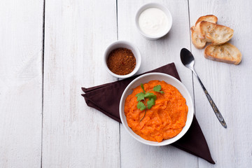 Pumpkin dish with toasted baguette slices, sour cream and spices on a brown cloth napkin.