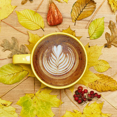 Autumn flat lay composition with dry leaves wreath frame and coffee latte cup on wooden background. 