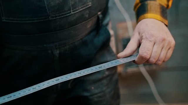 Carpentry industry - a woodworker measuring the wooden piece with a yardstick