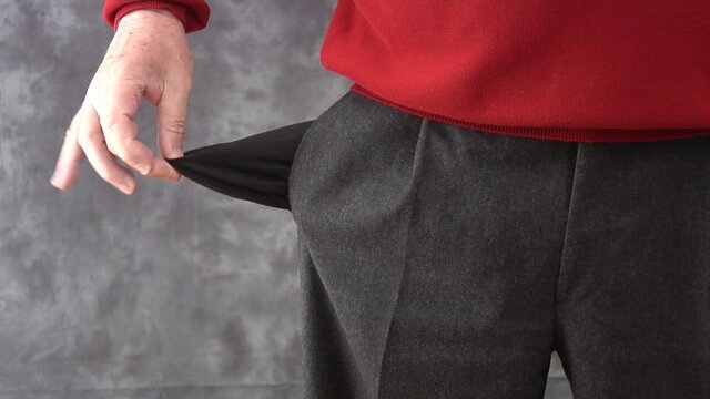 Man turning out his trouser pocket, revealing it to be empty.