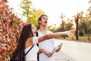 Young couple of tourists consulting a city guide and the digital tablet gps in the street searching locations