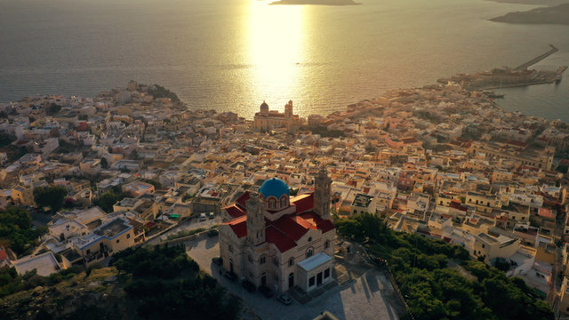 Aerial drone photo of iconic uphill Catholic settlement of ano Syra featuring church of Saint George at sunset with beautiful colours, Syros or Siros island, Cyclades, Greece