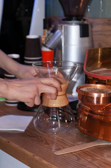 cropped view of barista holding glass flask on wooden table in caffe