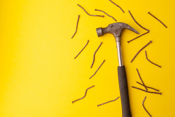 Old hammer and rusty nails. Yellow background