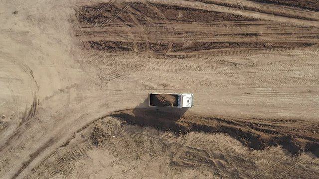 Large Truck hauling a full load of Excavated Soil on a dirt road, Top down aerial follow footage.