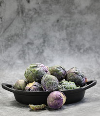A Bowl of Brussels Sprouts on grey background.