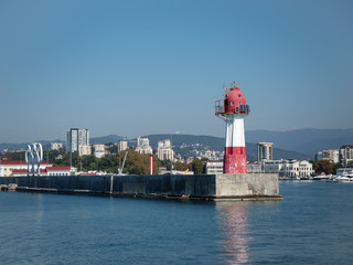 Red lighthouse with birds on a pier in the sea