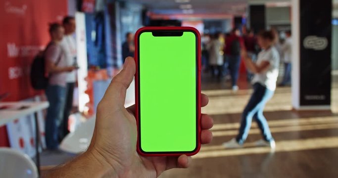 Man hand using blank green screen smartphone in business forum educating event. Woman taking photo for friends. Freelance visitors. Free pay. Educating lifestyle. IT desinging technology. Chromakey