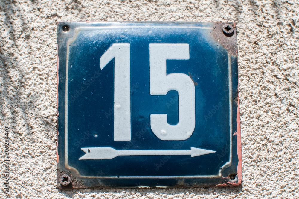 Wall mural weathered grunge square metal enameled plate of number of street address with number 15 closeup