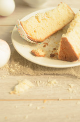 Holiday of Easter.Top view, slices of sweet Easter cake on a plate and Easter eggs on a light wooden background,copyspace in the down.