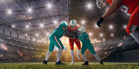 Obraz na płótnie Canvas American football players on professional stadium on sunset.