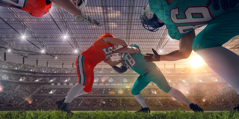 American football players on professional stadium on sunset.