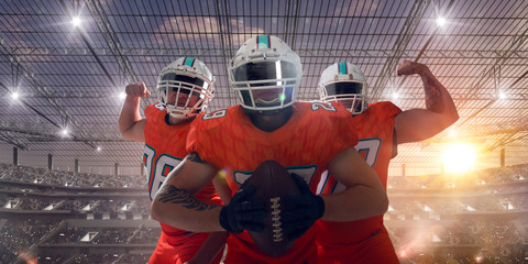 American football players on professional stadium on sunset.