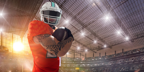 American football players on professional stadium on sunset.