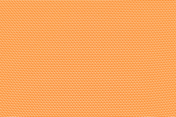 Light orange background from a textile material with pattern, closeup. Structure of bittersweet color fabric with punching texture. Perforated cloth backdrop..