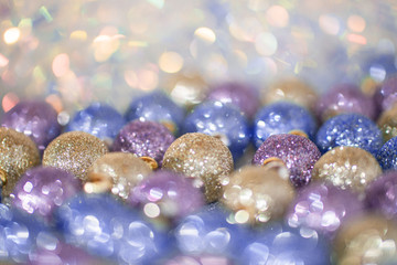 Blurred image of bright violet, blue and gold Christmas toys on sparkle background. Soft focus and beautiful  bokeh.