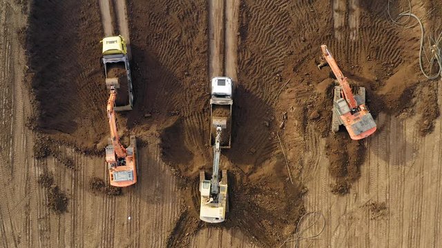 Vast Excavation site with an on going operation of Excavators loading soil onto Trucks, Aerial view.