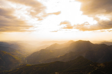 Fototapeta premium Fabulous view from Moro Rock at Sequoia National Park with a foggy mountains on background and beautiful sun rays highlighting the horizon ,