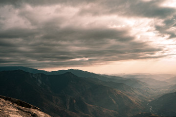 Fabulous view from Moro Rock at Sequoia National Park with a foggy mountains on background and beautiful sun rays highlighting the horizon