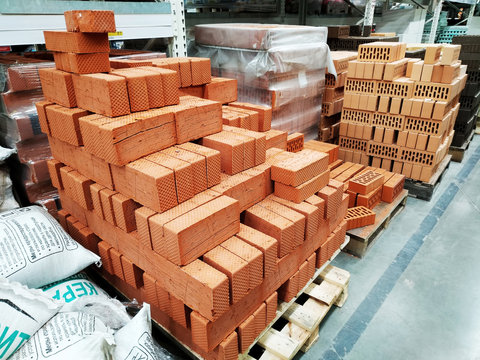 Pallet with red bricks are sold in a large building materials store