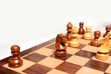Top angle shot of chess pieces on chessboard against white background. Wooden chess pieces.