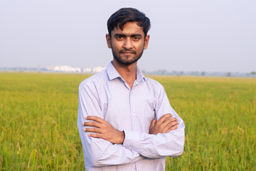 Portrait of young Indian Farmer wearing formal dress in green paddy field.