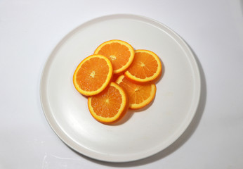 The thin round pieces of orange slices put together on the white dish.