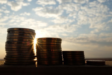 Decreasing stack of coins at sunset showing business failure concept