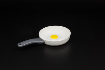 Children's plastic toy white pan omelette closeup on black background