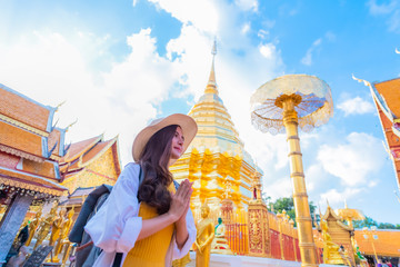 A young woman praying at Wat Phra That Doi Suthep, a famous tourist attraction and places of interest in Chiang Mai, Thailand - obrazy, fototapety, plakaty