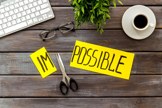 All is possible concept. Cut word impossible near scissors on dark wooden office desk