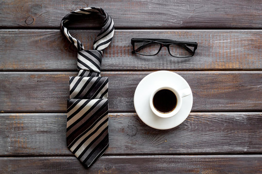 Father's birthday concept. Men's tie, coffee, glasses on dark wooden background top-down