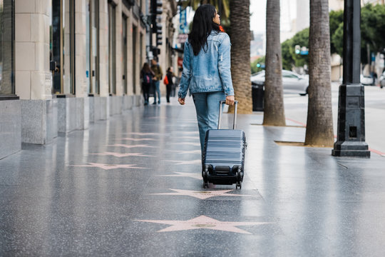 young woman with luggage walking on the street