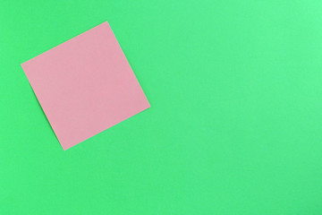Empty pink sticker note on a green background. Business concept, horizontal mock-up